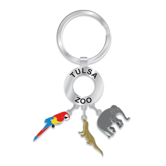 The Tulsa Zoo Dangle Keychain is a round silver keychain with "TULSA ZOO" on it and three charms: a colorful parrot, green lizard, and gray elephant—ideal for wildlife sanctuary fans.