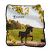 A soft Frederik Meijer Gardens & Sculpture Park Horse Raschel Blanket featuring a bronze horse sculpture on a grassy hill, with the park logo printed in the upper left corner.