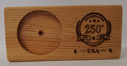 The USA 250th Anniversary Wood Coin Holder is a rectangular plaque made from reclaimed wood, with a left-side round slot for a USS Constitution coin and an engraved "Celebrating 250 Years USA" design with stars and laurels on the right.