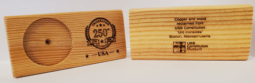Two wooden plaques are displayed: one is the USA 250th Anniversary Wood Coin Holder with a commemorative emblem, and the other features engraved text about USS Constitution wood along with the museum logo.
