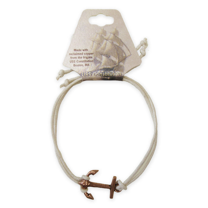 The Adjustable Cord Bracelet features a small copper anchor charm made from reclaimed USS Constitution copper, on a white cord, displayed on a card with a ship illustration and details about its Boston, MA origin.