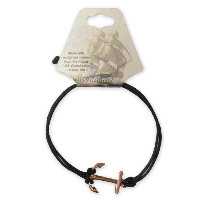 The Adjustable Cord Bracelet with USS Constitution Copper Anchor Charm features a black cord and small anchor made from reclaimed USS Constitution copper, presented on a card with a ship illustration and Boston, MA details.