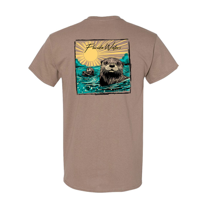 Introducing the Mote Marine Laboratory Florida Waters River Otter T-Shirt—a tan tee featuring a vibrant graphic on the back of two otters swimming beneath a bright sun, with the words “Florida Waters River Otter” displayed above. Ideal for marine conservation enthusiasts, this shirt celebrates native wildlife and helps raise awareness for Florida’s aquatic habitats.