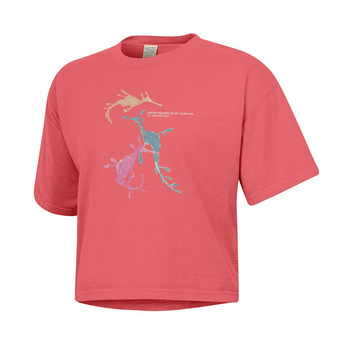 Salmon-colored cropped t-shirt featuring a graphic of three seadragons and the text Birch Aquarium at Scripps, La Jolla, San Diego.