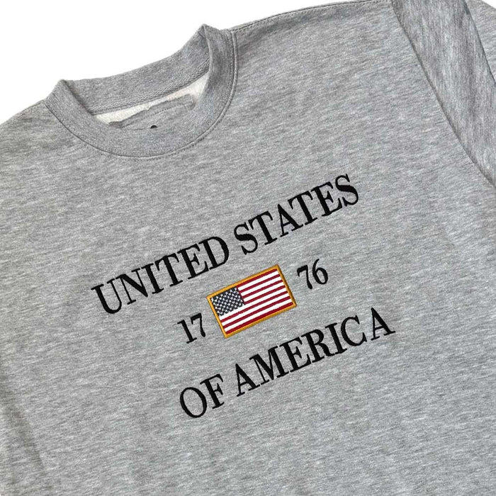 Show your patriotic spirit with the United States Icon Crew Sweatshirt, featuring bold "UNITED STATES OF AMERICA," 17 and 76 flanking an American flag—a stylish nod to American history for everyday pride.