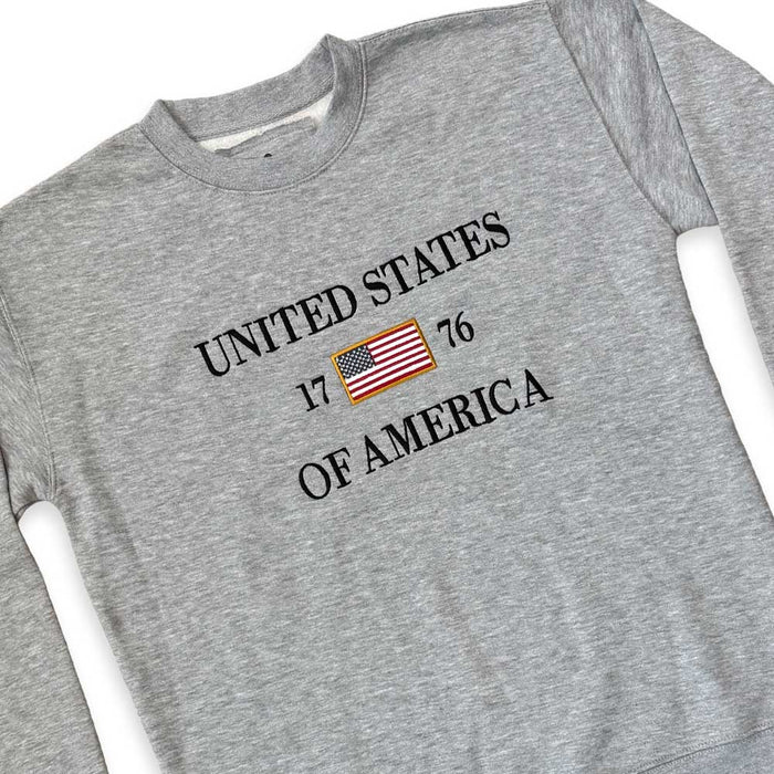 The United States Icon Crew Sweatshirt is a gray patriotic crewneck with “UNITED STATES 1776 OF AMERICA” and an American flag patch between 17 and 76—ideal for American history fans.