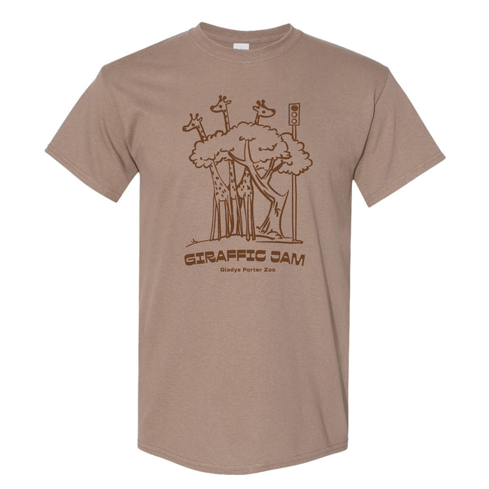 Tan t-shirt featuring a brown line drawing of giraffes gathered around a tree at a traffic light, with the text GIRAFFIC JAM and Gladys Porter Zoo below.