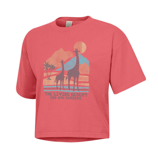 The Living Desert Zoo and Gardens Women’s Crop T-Shirt—a pink crop top featuring two giraffes, palm trees, mountains, and a sun with “The Living Desert Zoo and Gardens” text on the front—is perfect for stylishly supporting wildlife conservation.