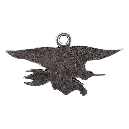 The Navy SEAL Museum Pewter Ornament is a handcrafted, dark metal pendant depicting an eagle in flight clutching a trident and a flintlock-style pistol, with a small loop at the top for hanging—this striking ornament is inspired by artifacts displayed at the Navy SEAL Museum.