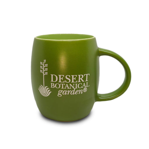 The Desert Botanical Garden Etched Mug is a green ceramic mug featuring a white plant logo and the words “Desert Botanical Garden” on the front. Its rounded shape and large handle make it a perfect gift for botanical garden lovers while celebrating Arizona’s native flora.