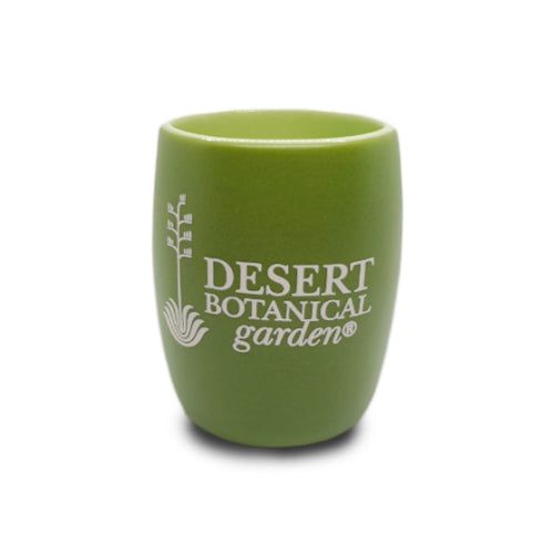 Raise a toast to desert flora with the Desert Botanical Garden Etched Shot Glass. This small, green ceramic cup features "DESERT BOTANICAL GARDEN" and a stylized plant logo printed in white on the front, capturing the spirit of the garden in every detail. A charming way to commemorate your visit or love for desert plants, it offers a unique alternative to traditional shot glasses.