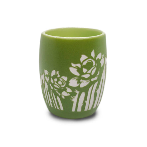 A small green ceramic Desert Botanical Garden Etched Shot Glass featuring white floral and leaf patterns inspired by desert flora on the exterior, displayed against a plain white background.