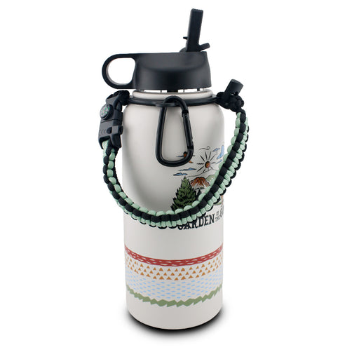 The Garden of the Gods Feeling Folksy Water Bottle is an eco-friendly white water bottle featuring a black lid, a straw, a green-and-black braided handle, a black carabiner, and vibrant outdoor-themed designs with mountains, the sun, and geometric patterns—perfect for any Colorado water bottle collection.