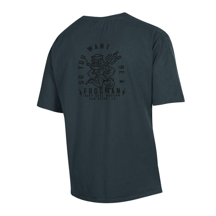Navy SEAL Museum Frogman Pocket T-Shirt in dark blue, showcasing a black back graphic of a cartoon frog in scuba gear with a trident. Surrounding the illustration is text that reads, “So You Want To Be A Frogman, Navy SEAL Museum, San Diego, CA”—a fitting tribute to Navy SEALs’ heritage and style.