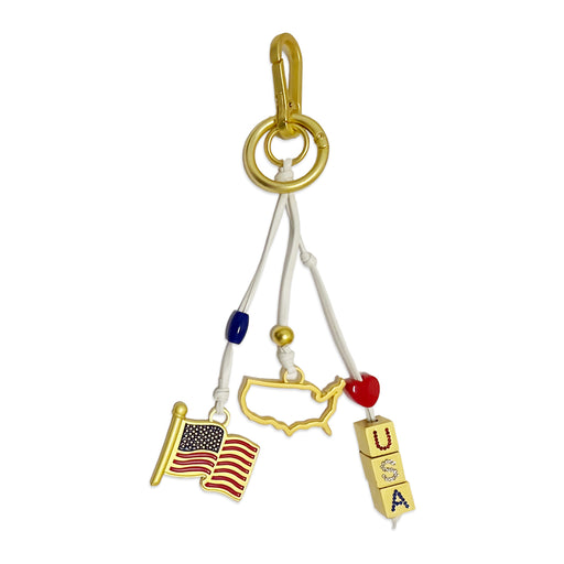 The USA Icon Trio Bag Clip features three charms—a gold USA outline, an American flag, and blocks spelling "USA"—all attached to a gold ring with colored beads and white cords. It's the perfect patriotic accessory for showing your American pride!.
