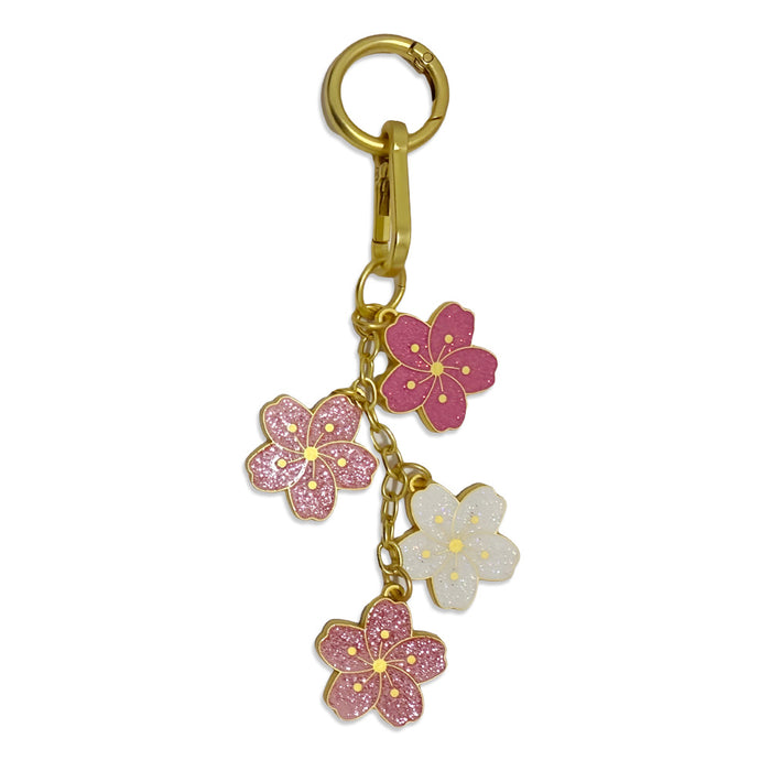 The Cherry Blossom Dangle Bag Clip features four pink and white glittery cherry blossom charms with gold accents, creating an elegant botanical accessory to add to your purse.