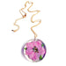 The Sakura Cherry Petal Necklace is a gold chain with a round, clear pendant that showcases a preserved pink flower and green leaves, inspired by Japanese jewelry for a timeless, nature-inspired look.