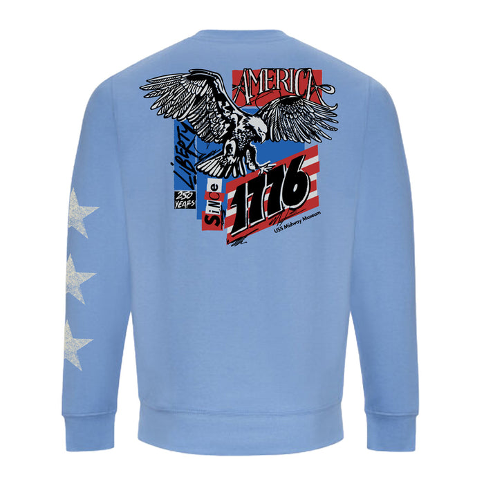 USS Midway Museum American Concert Tour Crew Sweatshirt in light blue, featuring three white stars on the sleeve. The back displays an eagle, red and white stripes, “AMERICA,” “Liberty,” “Since 1776,” and “250 Years with US Military Museum” text—celebrating American naval aviation history as seen at the USS Midway Museum in San Diego.