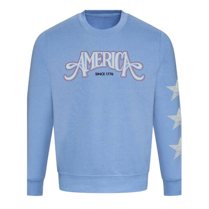 The USS Midway Museum American Concert Tour Crew Sweatshirt features a light blue color with “AMERICA SINCE 1776” in decorative lettering on the chest and three white stars on the left sleeve, drawing inspiration from the proud legacy of American naval aviation history and echoing classic styles found in San Diego’s USS Midway Museum sweatshirt collection.