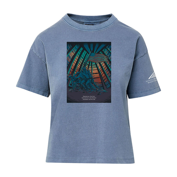 The National Museum of the Marine Corps Building Women’s T-Shirt features a colorful graphic of soldiers raising a flag with rays and a sunset in the background, plus text beneath the image. A small white logo inspired by the National Museum of the Marine Corps appears on the left sleeve, making this a standout patriotic shirt for women.