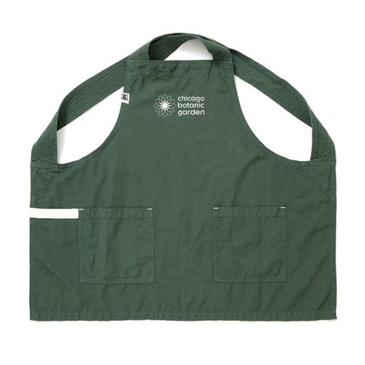 The Chicago Botanic Garden Gardening Smock is dark green with two front pockets and a white logo on the chest. Made from a linen-cotton blend, it features wide straps and a clean look, perfect for your next gardening project.