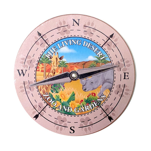The Living Desert Zoo and Gardens Compass Spinner Magnet features a round design with animal paw prints, illustrations of a giraffe and rhinoceros, and is labeled “The Living Desert Zoo and Gardens,” making it a unique keepsake celebrating desert ecosystems.