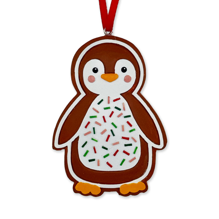 The Lincoln Park Zoo Gingerbread Penguin Ornament features a penguin-shaped design with a white belly adorned with red, green, and black sprinkles, orange feet, and a red ribbon for hanging.