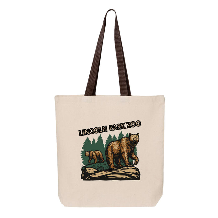Lincoln Park Zoo Brown Bear Scene Tote: This canvas tote bag with brown straps features an illustration of two bears among pine trees and the text “Lincoln Park Zoo.” Ideal for wildlife conservation enthusiasts, the main bear stands on a log while another bear appears in the background.