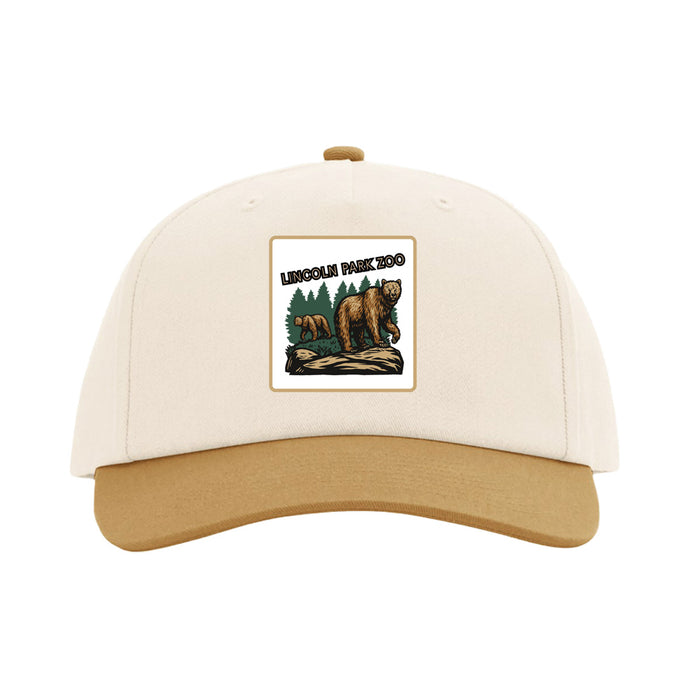 The Lincoln Park Zoo Brown Bear Scene Cap is a beige and tan baseball cap with a patch featuring two bears, trees, and the text “Lincoln Park Zoo” on the front—perfect for showing your support of wildlife conservation while coordinating with your favorite Lincoln Park Zoo tote.