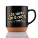 The Garden of the Gods Colorful Colorado 150th Mug features a black design with a cork base, vibrant “Colorful Colorado” lettering, and “Celebrating Colorado’s 150th” below. Mountain scenery, native flowers, and a bear illustration surround the text, making this the ideal collectible mug for anyone who appreciates the beauty of Garden of the Gods.