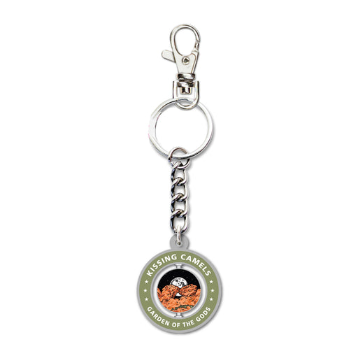 Introducing the Garden of the Gods Kissing Camels Spinner Keychain—a round keychain with a durable metal chain and clip. The spinning charm showcases vibrant imagery of red rock formations with “KISSING CAMELS GARDEN OF THE GODS” encircling the border in bold white letters, making it a perfect Colorado souvenir for fans of Garden of the Gods.