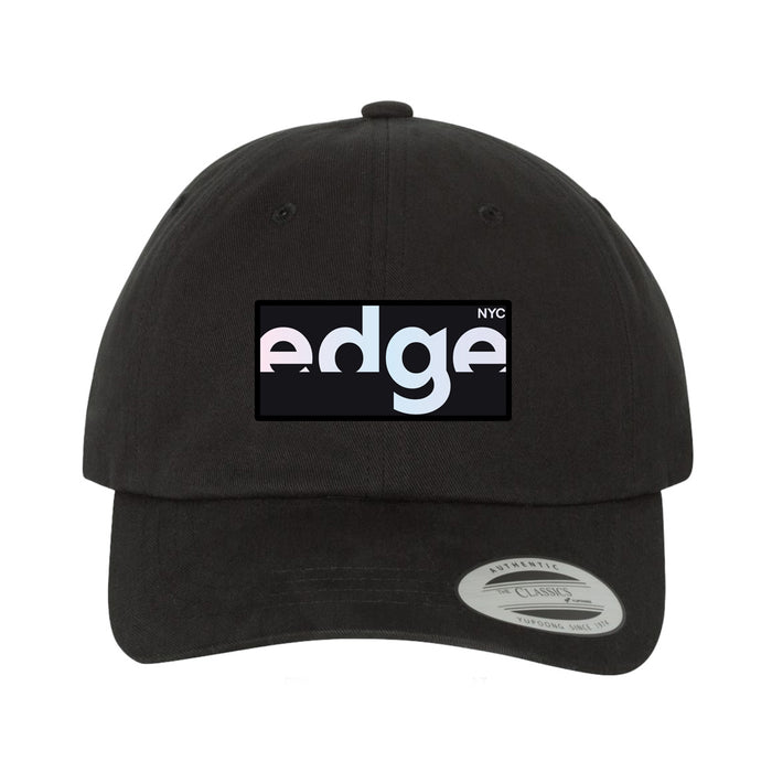 The Edge NYC Pearlescent Logo Patch Cap is a black hat featuring a rectangular, pearlescent patch with “edge NYC” in white and light blue lettering. A circular sticker on the brim reads “AUTHENTIC CLASSIC,” making it an excellent New York City souvenir.