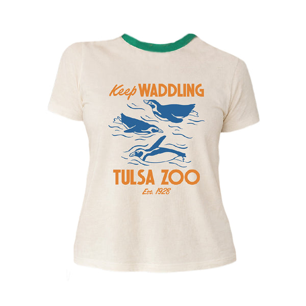 The Tulsa Zoo Penguin Sporty Pop Ringer T-Shirt is white with green trim, features blue penguin illustrations and orange "Keep Waddling Tulsa Zoo Est. 1928" text, and is made of organic cotton—perfect for sustainable fashion fans.