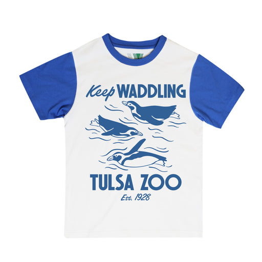 The Tulsa Zoo Penguin Sporty Pop Youth T-Shirt is a white and blue top with illustrations of swimming penguins and "Keep Waddling Tulsa Zoo Est. 1928" text on the front. Fair Labor Certified.