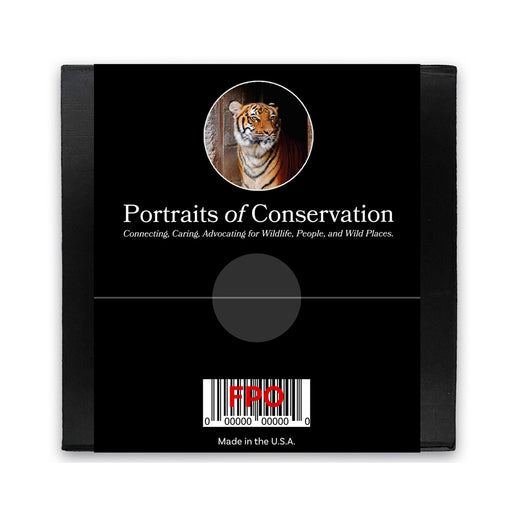 A black square package with a tiger photo at the top, 'Portraits of Conservation' title, and wildlife advocacy subtitle. Bottom includes barcode, FDO, and Made in the U.S.A.—the ideal gift or Tulsa Zoo Tiger Glass Paperweight.