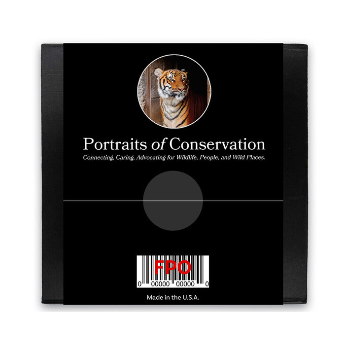 A black square package with a tiger photo at the top, 'Portraits of Conservation' title, and wildlife advocacy subtitle. Bottom includes barcode, FDO, and Made in the U.S.A.—the ideal gift or Tulsa Zoo Tiger Glass Paperweight.