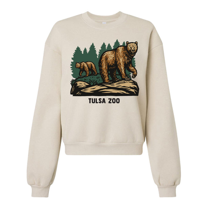 The Tulsa Zoo Brown Bear Women's Crew Sweatshirt features two bears on grass with pine trees and "TULSA ZOO" printed below, making it a perfect choice for zoo lovers.