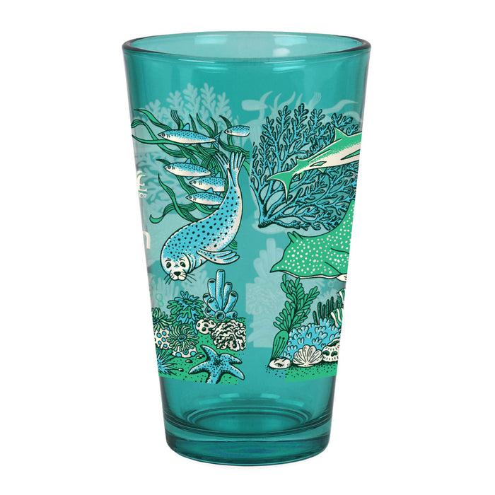 Seattle Aquarium Old Stove Brewing Co. Pint Glass featuring teal-colored illustrations of an underwater scene with a spotted seal, fish, coral, seaweed, a stingray, and seashells—perfect for Seattle Aquarium or Old Stove Brewing Co. fans.