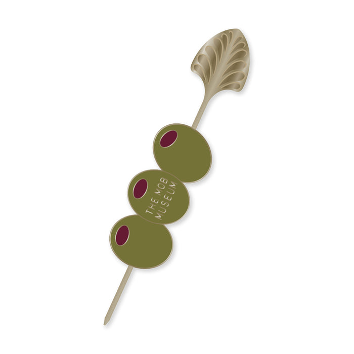 The Mob Museum Cocktail Stirrer Pin stylishly skewers three green olives—one inscribed with THE MOB MUSEUM—while its ornate, leaf-shaped top channels Prohibition-era elegance against a crisp white background.