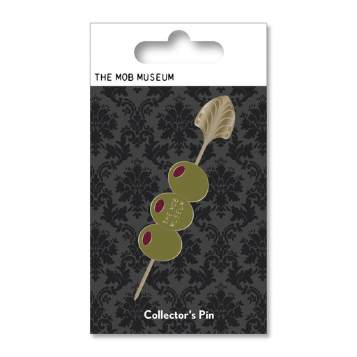 The Mob Museum Cocktail Stirrer Pin showcases three green olives on a cocktail stirrer, with one olive labeled THE MOB MUSEUM, set against a striking black patterned background. Inspired by the Prohibition era, the packaging reads “THE MOB MUSEUM” and “Collectors Pin,” making it an ideal piece for fans of unique memorabilia.