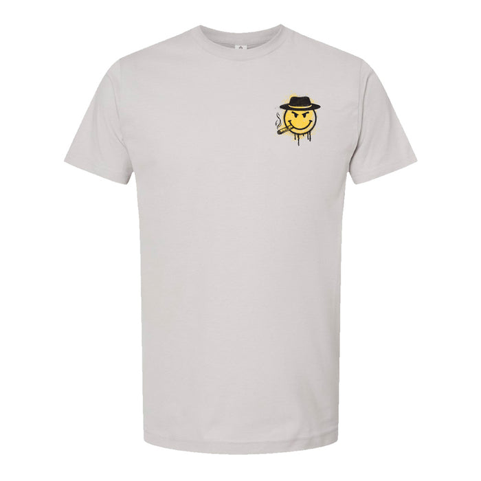 The Mob Museum Happy Face T-Shirt—a white tee showcasing a small graphic on the left chest of a sly, yellow smiley face in a black hat with a cigarette, capturing playful gangster vibes and making it an ideal Las Vegas souvenir.