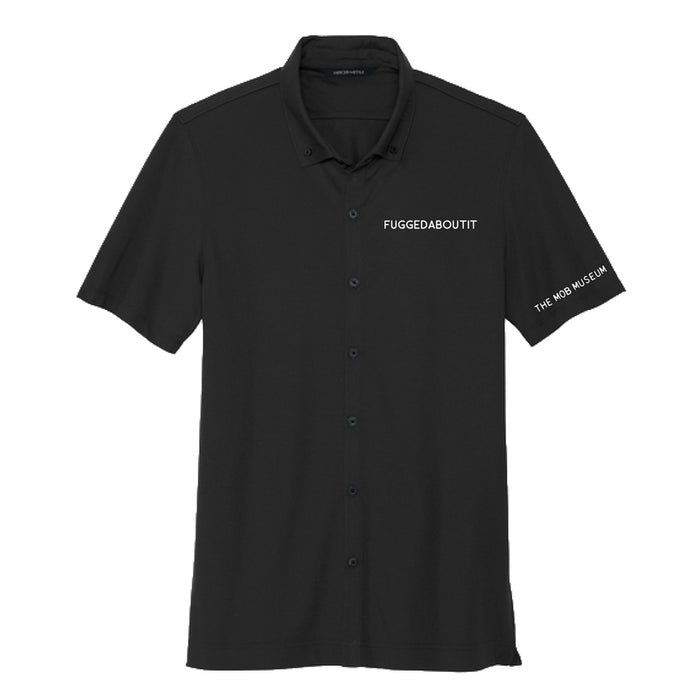 Introducing The Mob Museum Fuggedaboutit Button Up Polo T-Shirt—a black, short-sleeve men’s shirt with “FUGGEDABOUTIT” embroidered on the chest and “THE MOB MUSEUM” on the left sleeve in crisp white text. This standout piece brings a bold touch to any wardrobe.