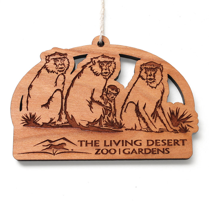 Introducing The Living Desert Zoo and Gardens Patas Monkey Wood Ornament—this wooden ornament features three etched monkeys above The Living Desert Zoo | Gardens text, accompanied by a mountain graphic on the left. Designed with a loop of string at the top for easy hanging, this unique ornament celebrates wildlife conservation and makes a charming addition to any African savanna decor.