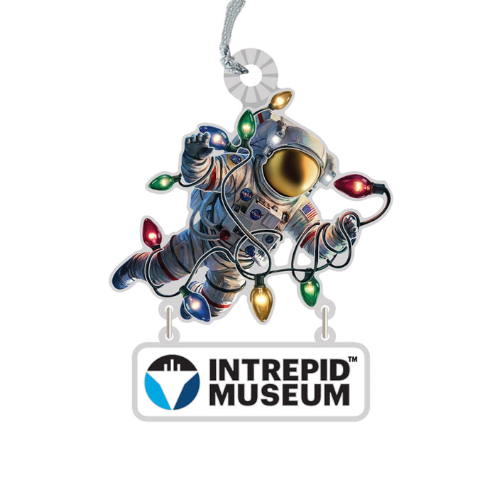 Celebrate space exploration with the Intrepid Museum Astronaut Lights Ornament, showcasing an astronaut holding vibrant holiday lights and attached to a sign that reads “Intrepid Museum,” complete with a handy hanging loop at the top.