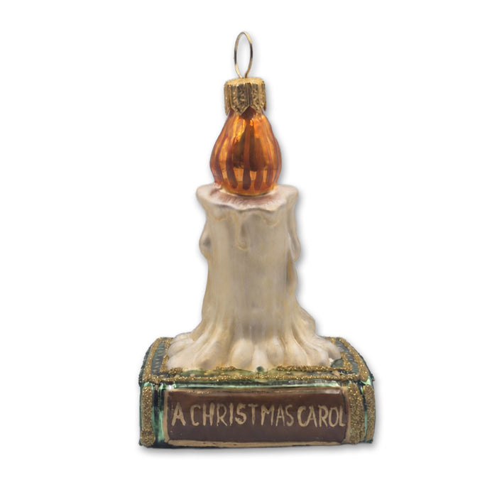 Glass Christmas tree ornament shaped like a candle resting on a book labeled A Christmas Carol.