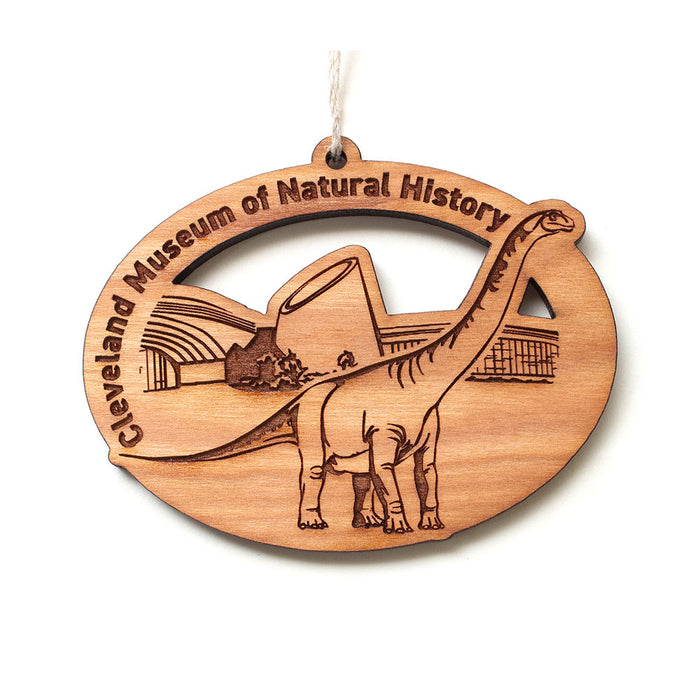 Oval wooden Cleveland Museum of Natural History Dino Wood Ornament engraved with a long-necked dinosaur in front of a building, with the museum name curved along the top edge.