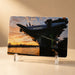 A printed photo of the USS Intrepid aircraft carrier at sunset stands upright on a clear plastic display holder, making it a perfect companion piece to the Intrepid Museum Ship Photo Magnet or a memento from the Intrepid Sea, Air & Space Museum.