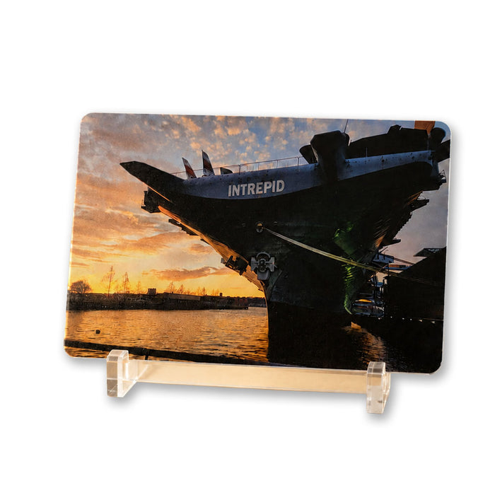 Bring home a stunning sunset view of the USS Intrepid aircraft carrier with the Intrepid Museum Ship Photo Magnet, featuring the renowned ship docked at the Intrepid Sea, Air & Space Museum as warm orange skies reflect on the water and its name stands out along the side.