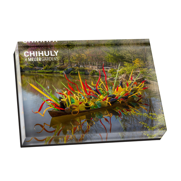 A rectangular Chihuly at Meijer Gardens Fiori Boat Magnet featuring a boat filled with colorful, abstract glass sculptures floating on a pond, with the text CHIHULY at MEIJERGARDENS printed in the upper left corner.