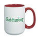 White mug with a red interior and handle, featuring the text Bah Humbug in green.